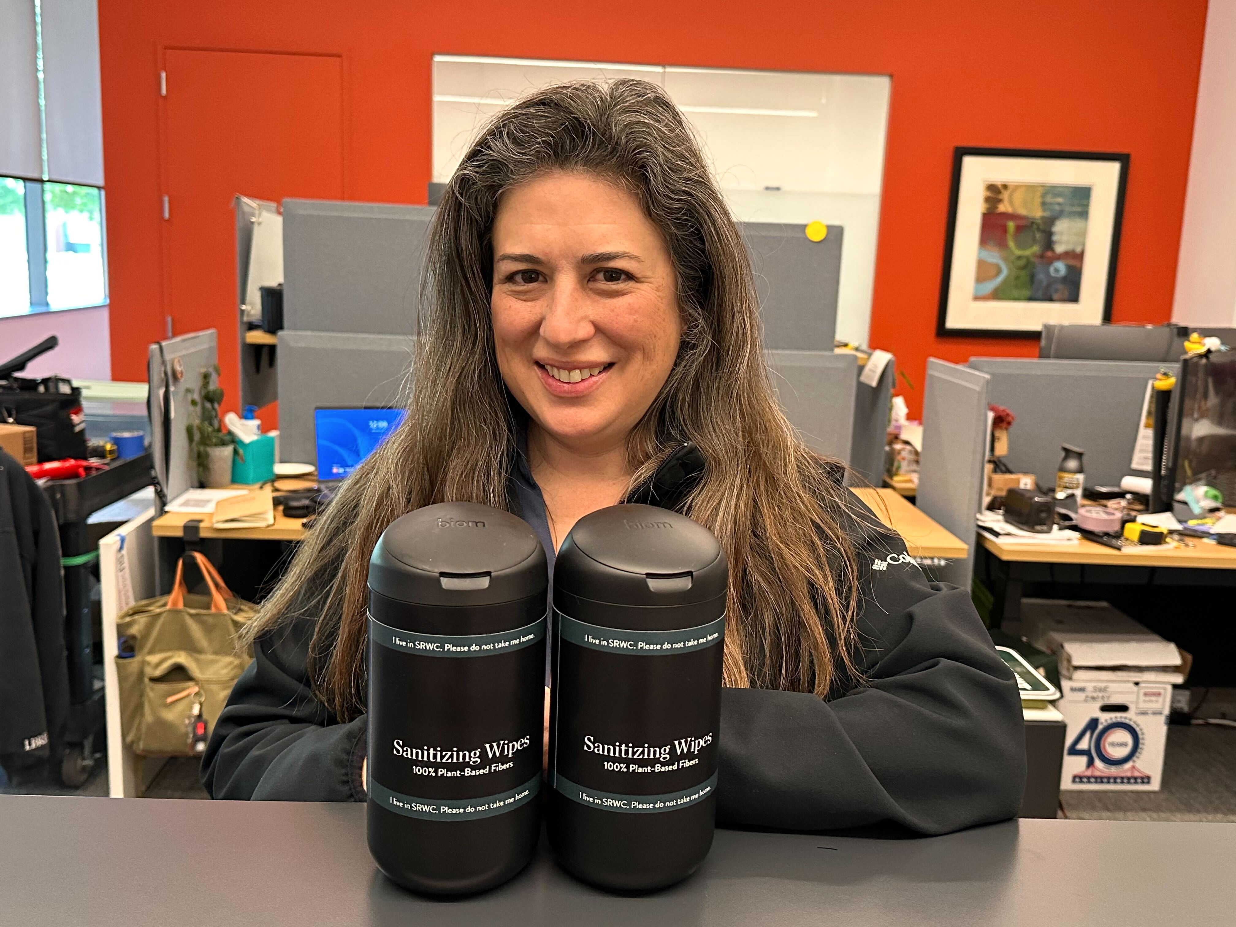 Person posing with two black containers of cleaning wipes.
