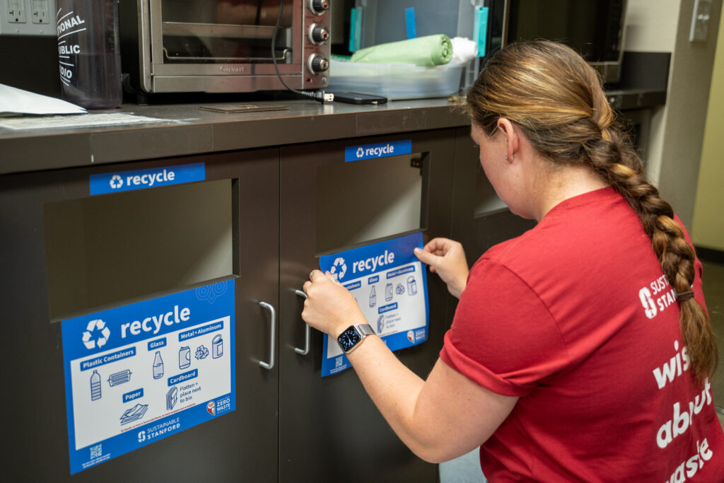 Person putting a recycling label on a cabinet.