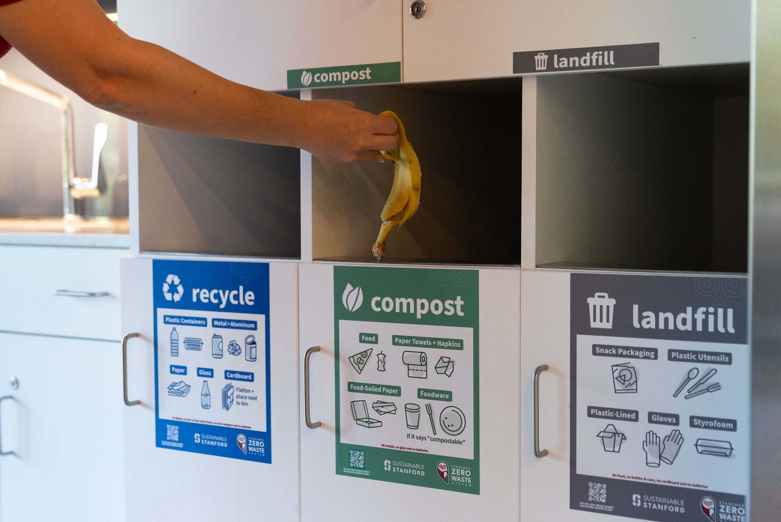 Someone throwing banana peel away in compost bin
