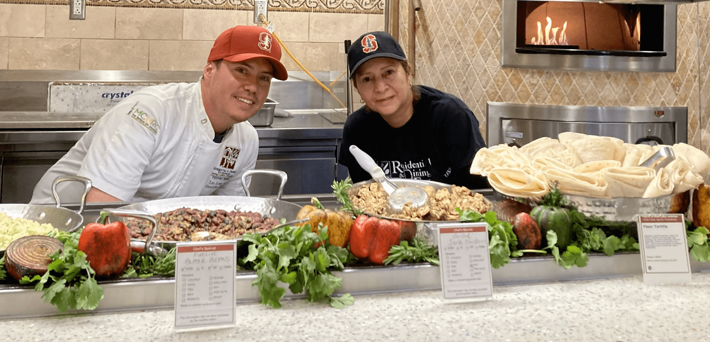 Dining hall cooks smiling with a variety of high quality food choices