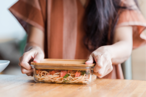 Person with a clear glass container with food inside.