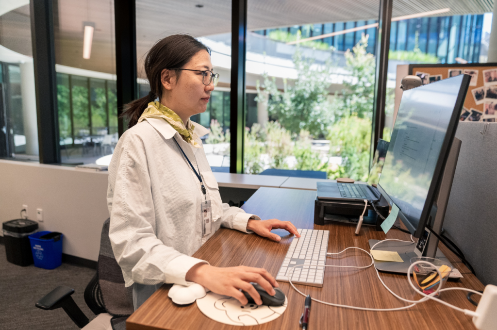 Faculty member working on a computer next to a window