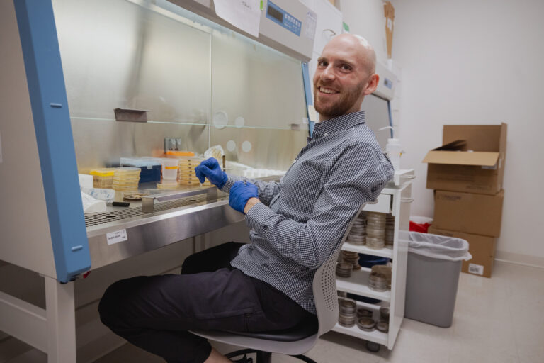Lab personnel wearing gloves and smiling