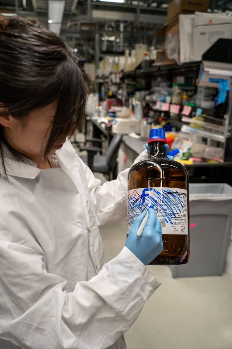 Lab personnel crossing off the label on a chemical bottle