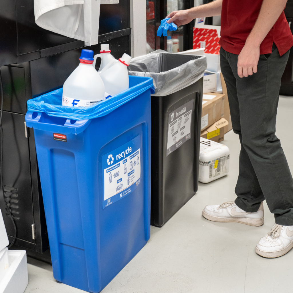 A blue recycle and black landfill bucket in a lab
