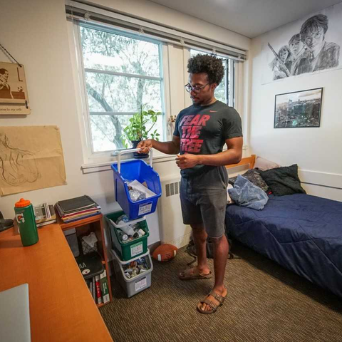 Student holding a compost bin in his dorm room