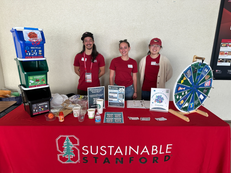 Student volunteers behind a table demonstrating sustainablity practices on campus