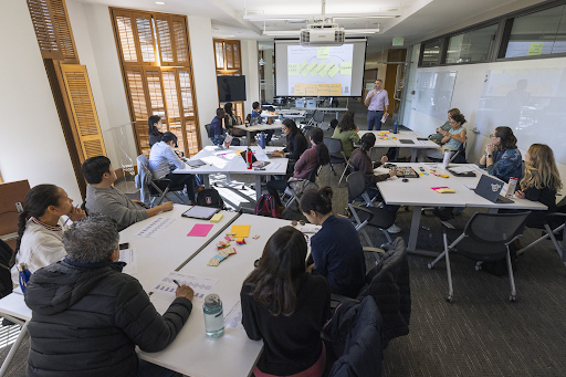 Group of people in a classroom meeting sitting at tables