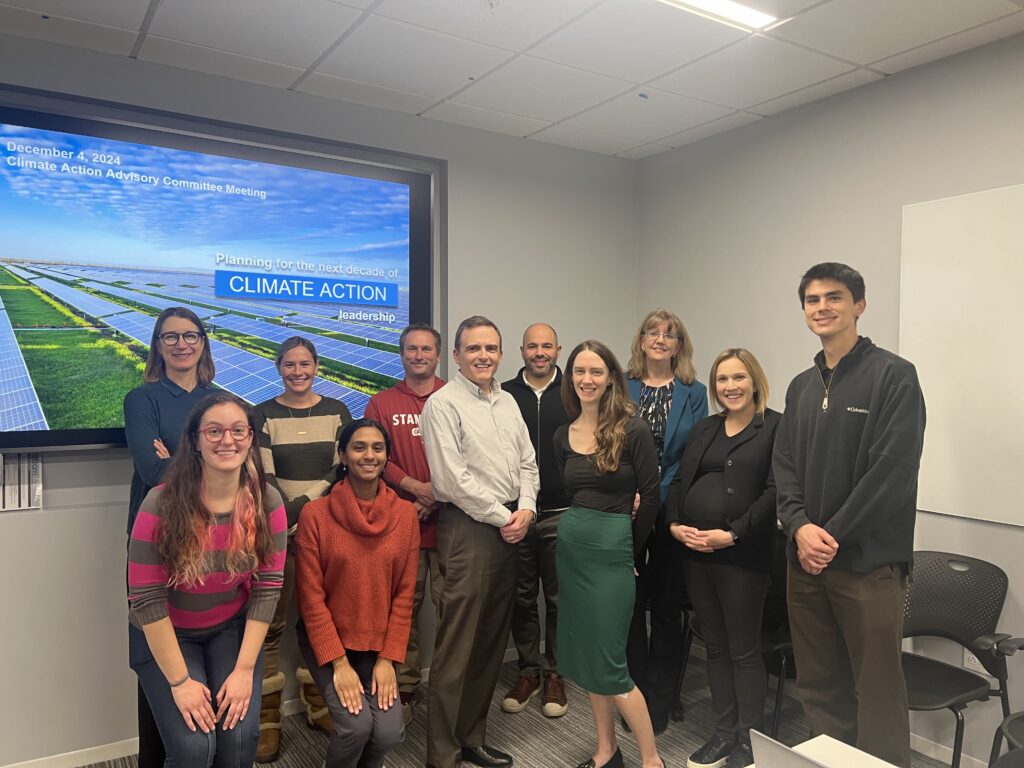 Photo of eleven staff, students, and faculty in front of a screen that reads "Climate Action"