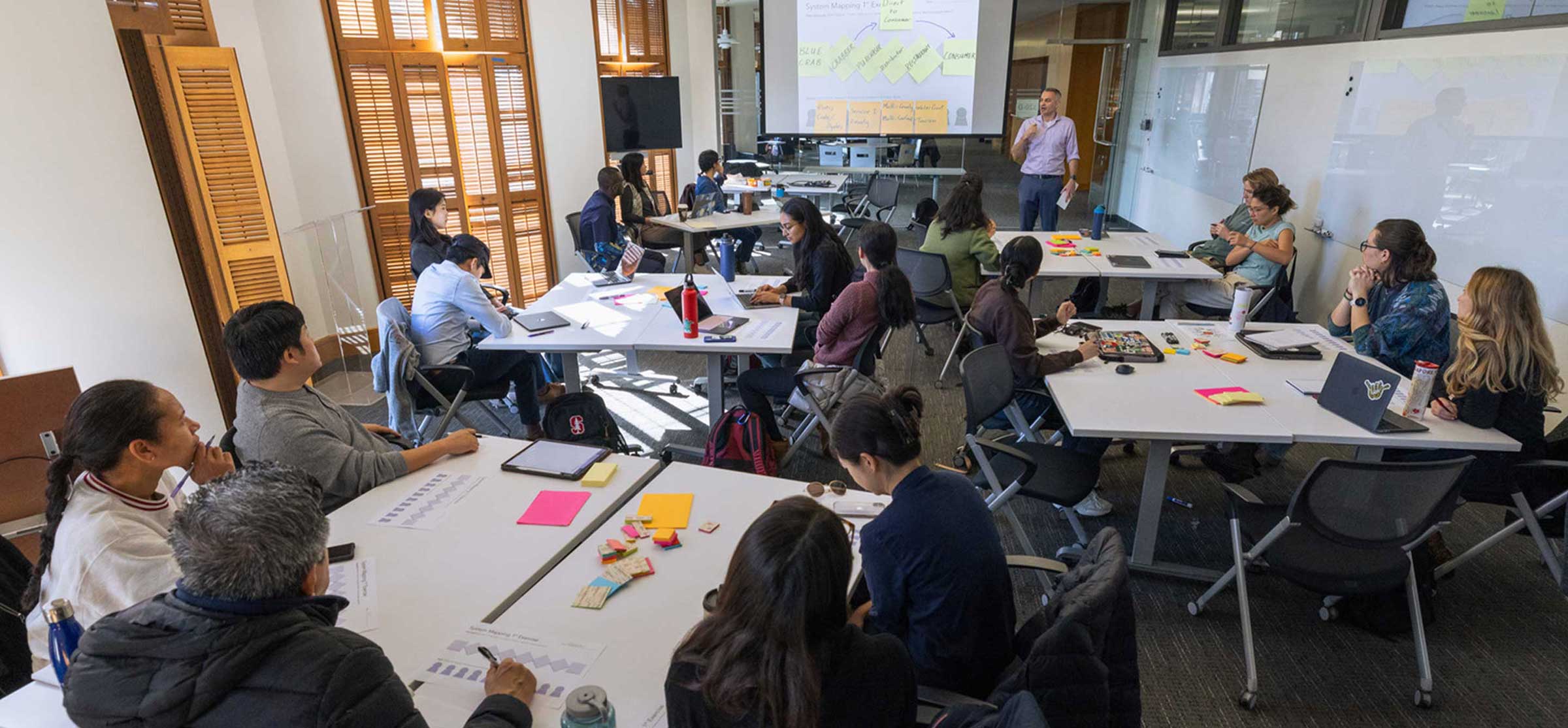 Students listen to a professor lecture during a design thinking workshop at Stanford University.
