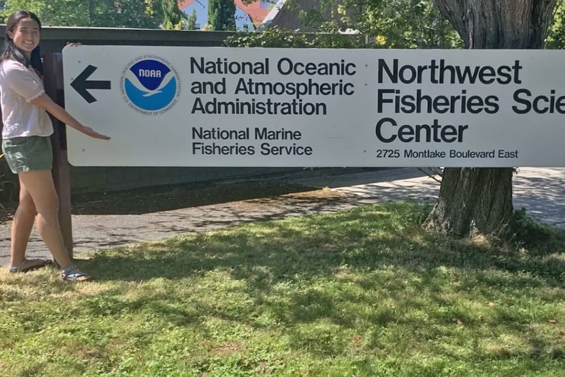 Student at Northwest Fisheries Science Center posing with sign