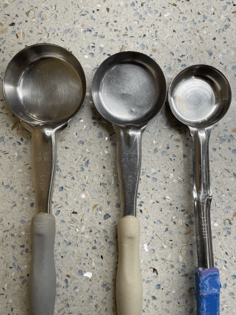 Spoons of varying sizes lined up next to each other from largest on left to smallest on right