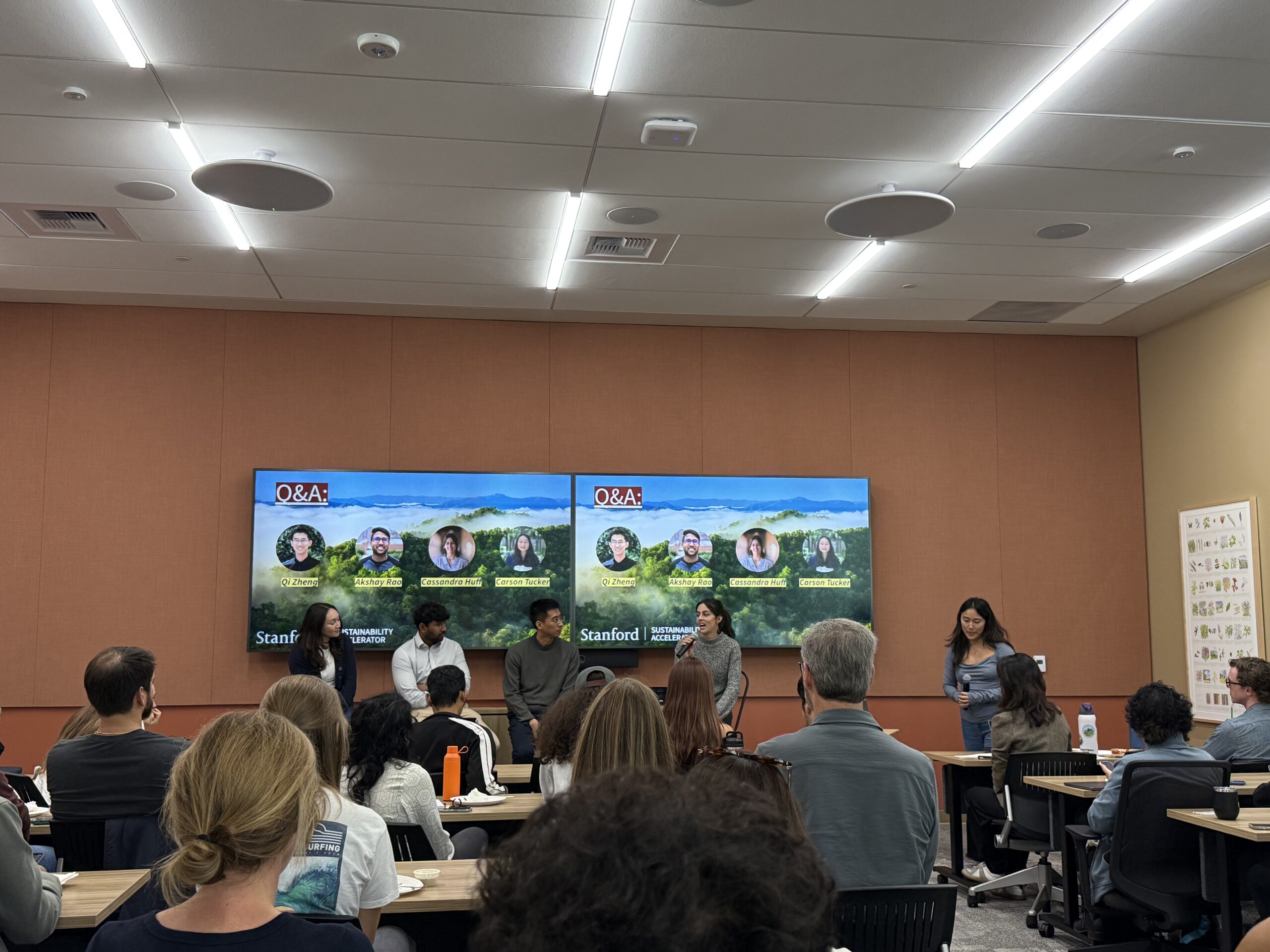 Students presenting at a panel for an audience in front of a screen that says "sustainability accelerator Q&A"